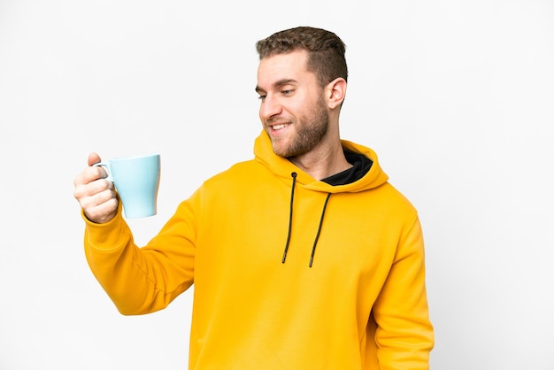 Joven apuesto hombre rubio sosteniendo una taza de café sobre un fondo aislado con expresión feliz