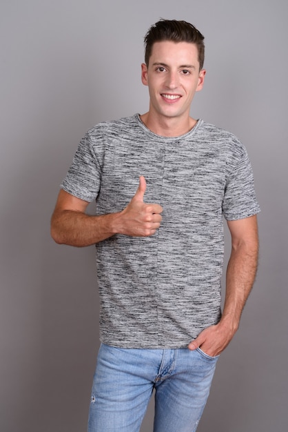 joven apuesto hombre vestido con camisa gris sobre gris