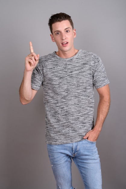 joven apuesto hombre vestido con camisa gris sobre gris