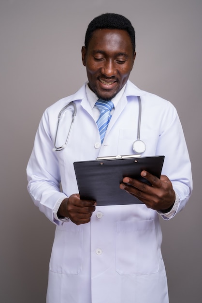 Joven apuesto médico africano contra el fondo gris