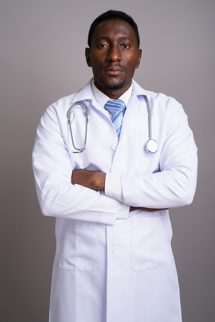 Joven apuesto médico africano contra el fondo gris