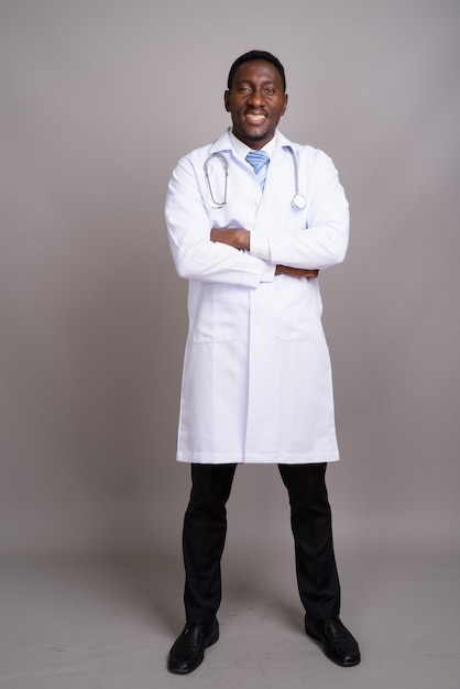 Joven apuesto médico africano contra el fondo gris