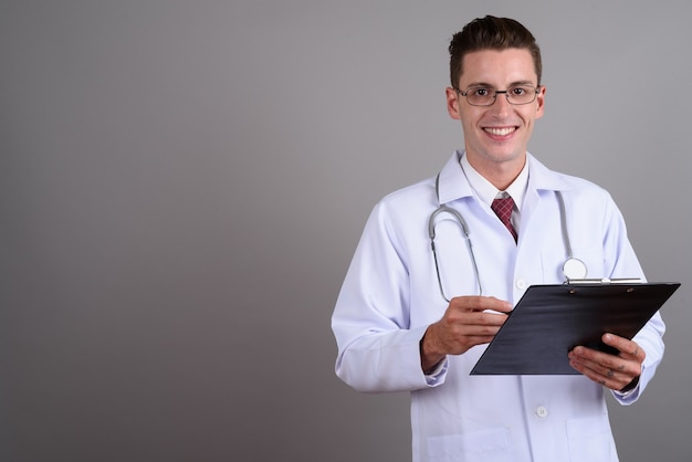 Joven apuesto médico con anteojos en gris