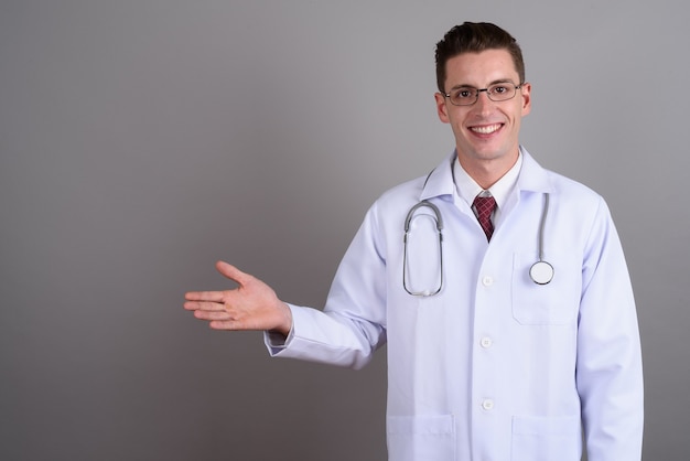 Joven apuesto médico con anteojos en gris