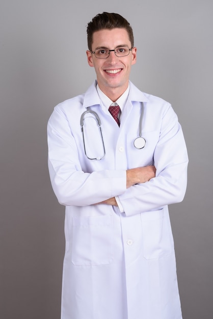 Joven apuesto médico con anteojos en gris