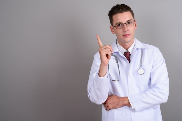 Joven apuesto médico con anteojos en gris