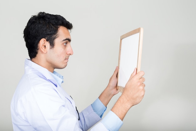 Joven apuesto médico indio contra la pared blanca