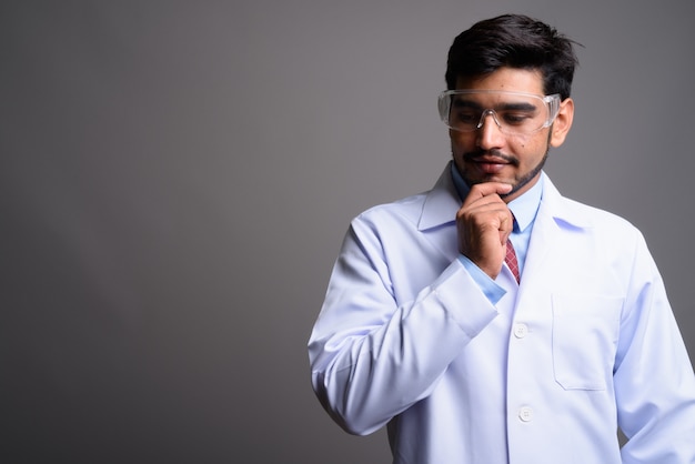 Joven apuesto médico persa barbudo con gafas protectoras