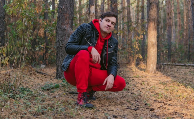 Un joven apuesto posa en el bosque de otoño al atardecer