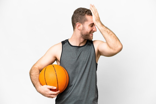 Un joven apuesto que juega baloncesto sobre un fondo blanco aislado se ha dado cuenta de algo y tiene la intención de encontrar la solución