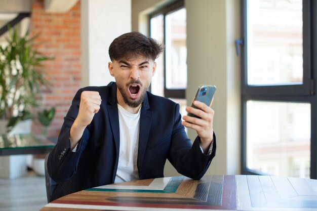 joven apuesto que parece enojado, molesto y frustrado. concepto de teléfono inteligente