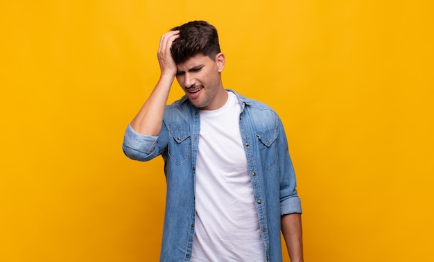 Joven apuesto riendo y dándose palmadas en la frente como diciendo dÃƒÂ ¢ Ã‚Â € Ã‚Â ™ ¡oh! Lo olvidé o fue un error estúpido