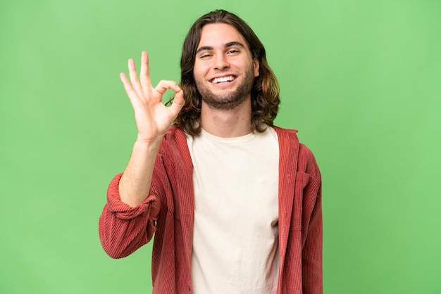 Joven apuesto sobre un fondo aislado que muestra el signo de ok con los dedos