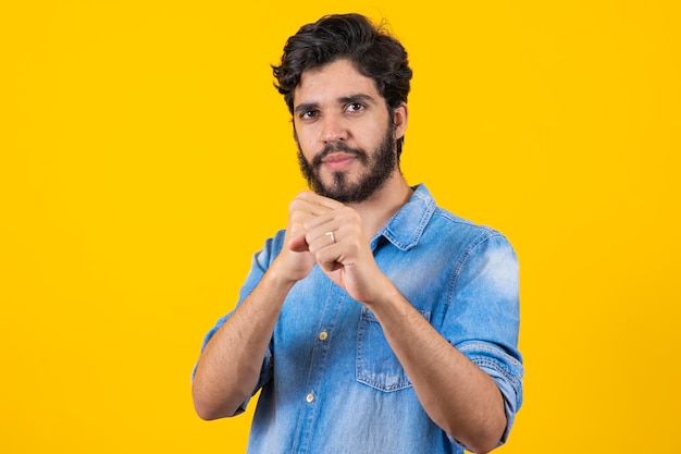 Foto joven apuesto sobre un fondo amarillo aislado golpeando el puño para luchar contra la amenaza y la violencia de ataques agresivos y enojados