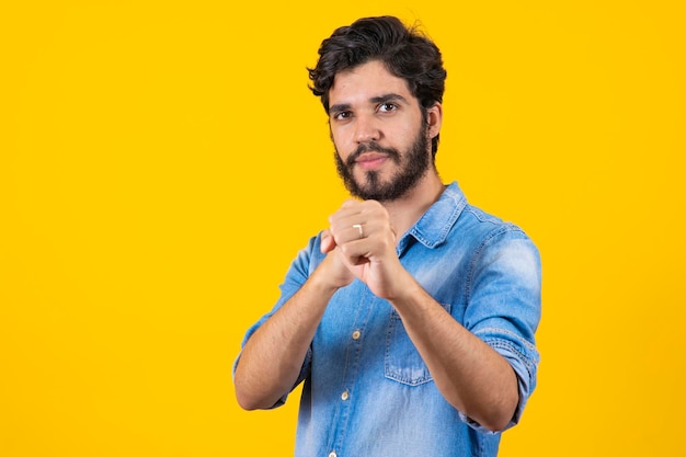 Foto joven apuesto sobre un fondo amarillo aislado golpeando el puño para luchar contra la amenaza y la violencia de ataques agresivos y enojados