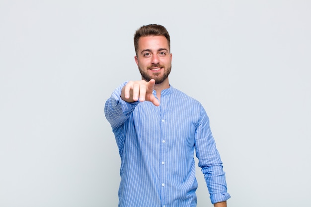 Foto joven apuntando a la cámara con una sonrisa satisfecha, confiada y amistosa, eligiéndote