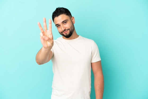 Joven árabe aislado sobre fondo azul feliz y contando tres con los dedos