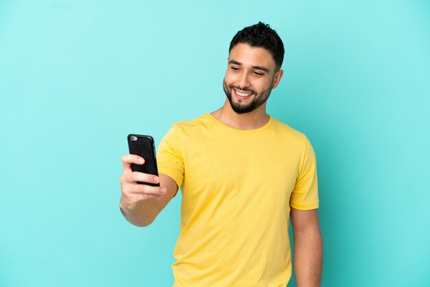 Joven árabe aislado sobre fondo azul haciendo un selfie