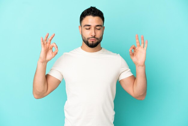 Joven árabe aislado sobre fondo azul en pose zen