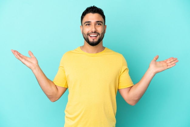 Joven árabe aislado sobre fondo azul sonriendo mucho