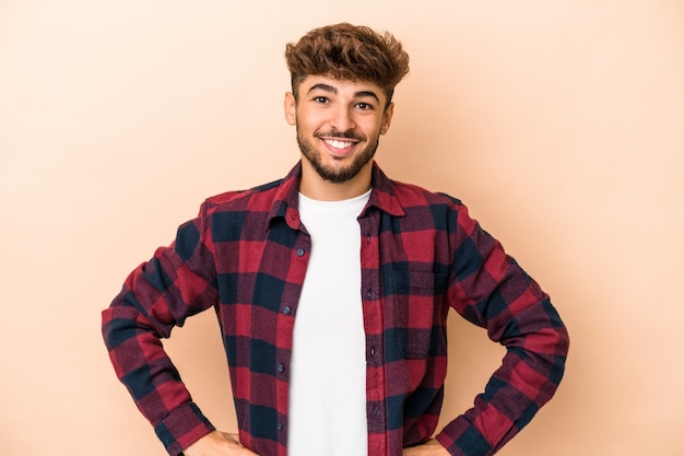 Joven árabe aislado sobre fondo beige feliz, sonriente y alegre.