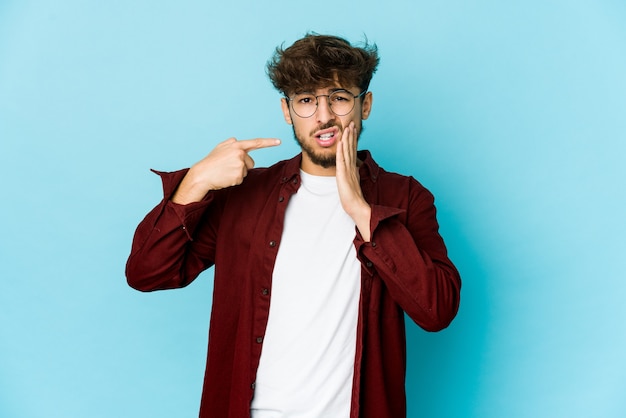 Joven árabe en azul con un fuerte dolor de dientes, dolor de muelas.