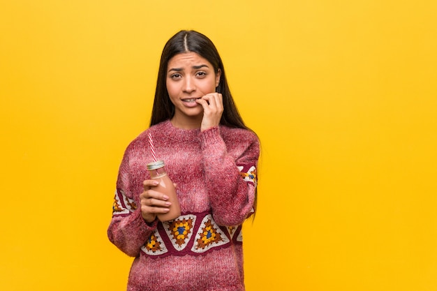 Foto joven árabe con un batido morderse las uñas, nervioso y muy ansioso.