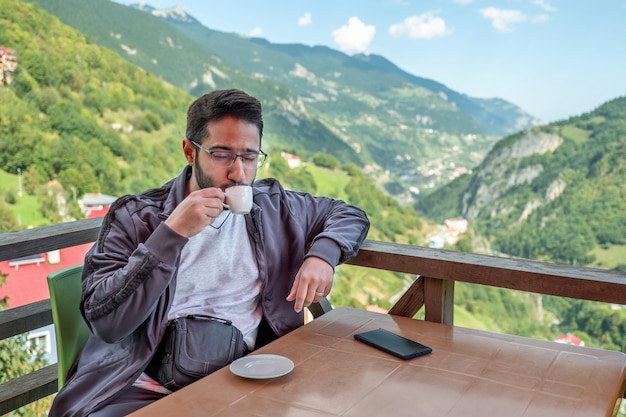 Joven árabe bebiendo café durante sus vacaciones en la naturaleza