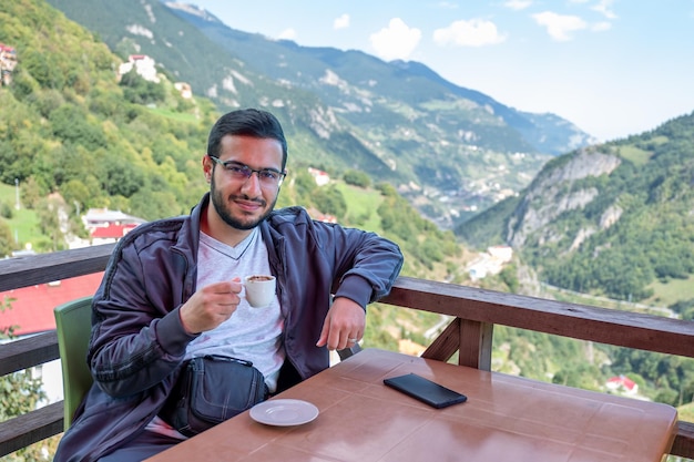 Joven árabe bebiendo café durante sus vacaciones en la naturaleza