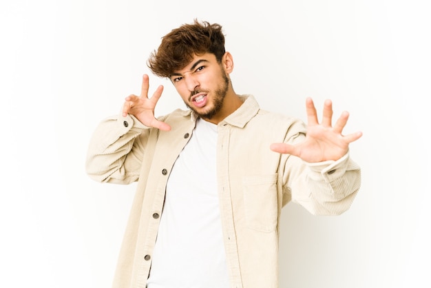 Joven árabe en blanco molesto gritando con las manos tensas.