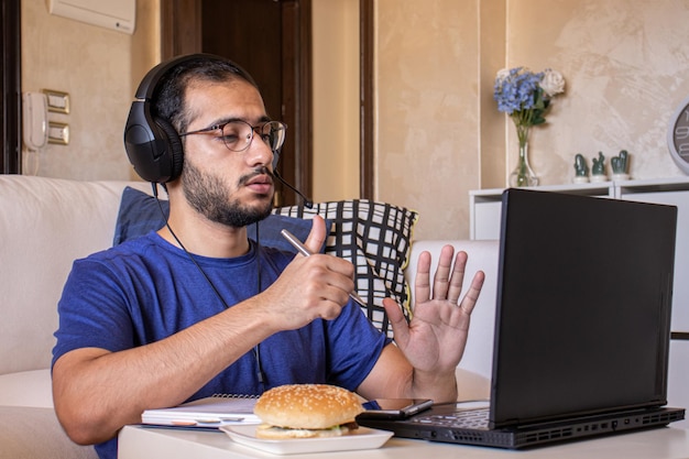 Joven árabe comiendo mientras trabaja y en casa