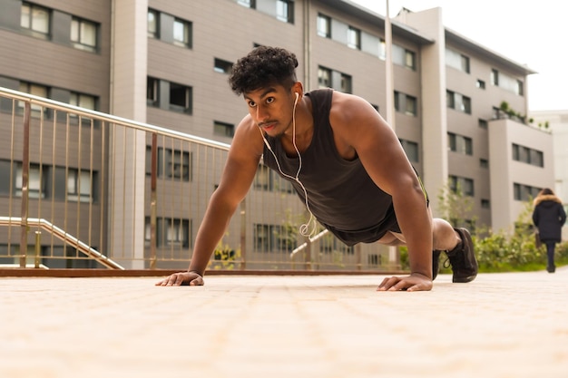 Joven árabe fuerte haciendo deportes en la ciudad haciendo algunas flexiones