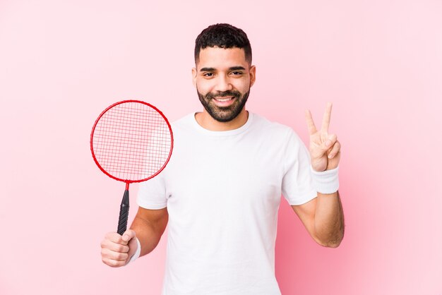 Joven árabe jugando bádminton mostrando el número dos con los dedos.