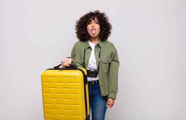 Foto joven árabe sintiéndose disgustada e irritada, sacando la lengua, disgustando algo desagradable y asqueroso concepto de viaje