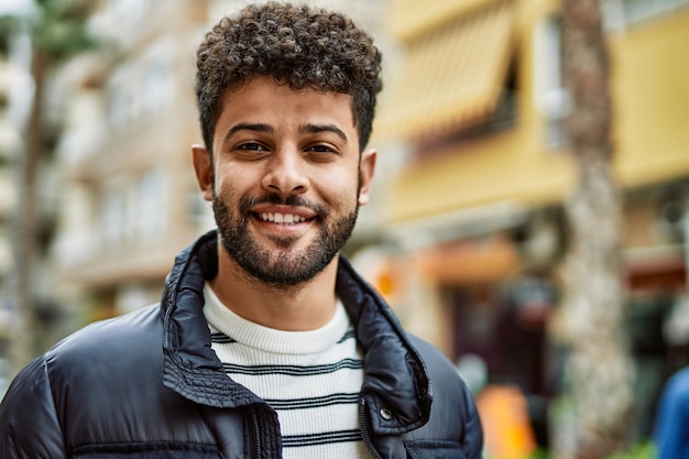 Joven árabe sonriendo al aire libre en la ciudad