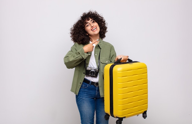 Joven árabe sonriendo alegremente, sintiéndose feliz y apuntando hacia un lado y hacia arriba, mostrando el objeto en el concepto de viaje de espacio de copia