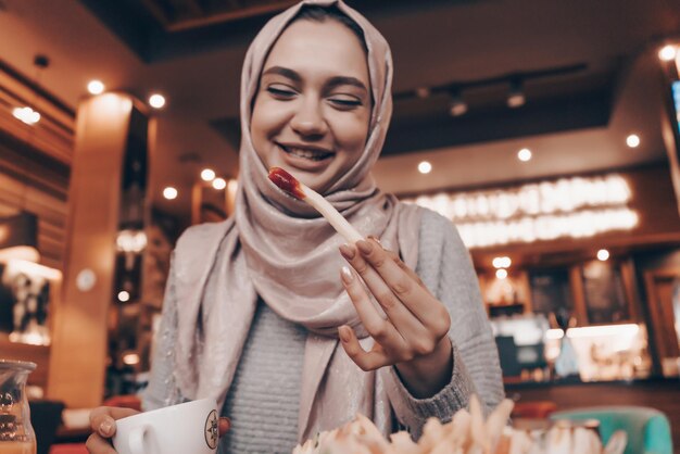 Una joven árabe sonriente con hiyab comió en un acogedor restaurante de buen humor y comida sabrosa