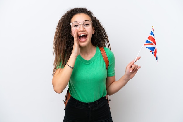 Joven árabe sosteniendo una bandera del Reino Unido aislada de fondo blanco gritando con la boca abierta