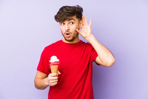 Joven árabe sosteniendo un helado tratando de escuchar un chisme.