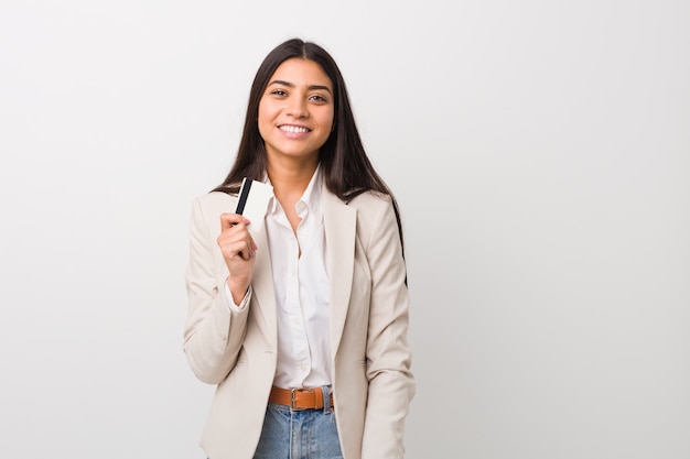 Joven árabe con una tarjeta de crédito feliz, sonriente y alegre.