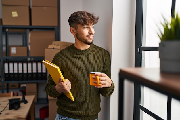 Joven árabe trabajador de negocios de comercio electrónico con cuaderno tomando café en la oficina