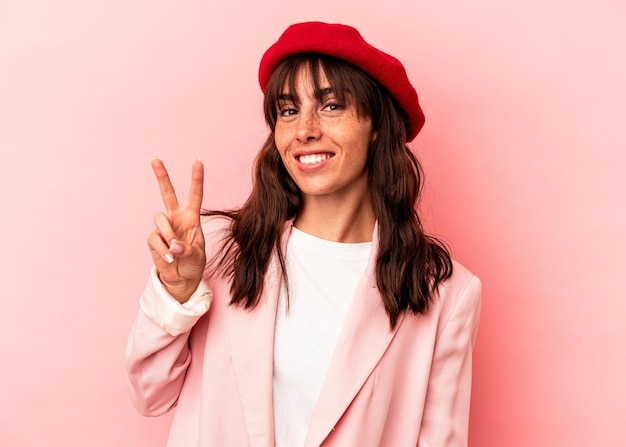 Joven argentina aislada de fondo rosa alegre y despreocupada mostrando un símbolo de paz con los dedos.