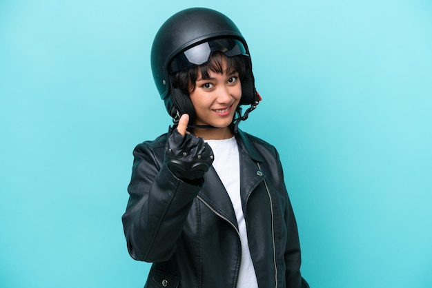 Joven argentina con un casco de motocicleta aislado de fondo azul haciendo gestos de dinero