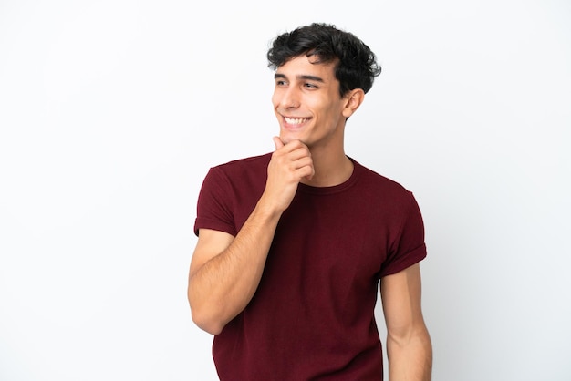 Joven argentino aislado de fondo blanco mirando hacia un lado y sonriendo