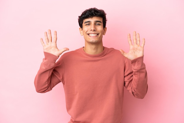 Joven argentino aislado de fondo rosa contando diez con los dedos