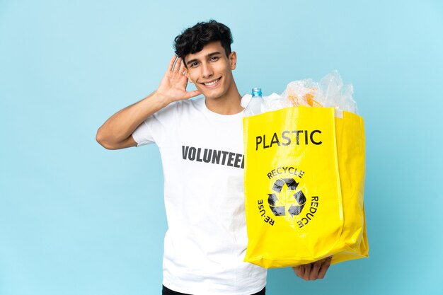 Joven argentino sosteniendo una bolsa llena de plástico escuchando