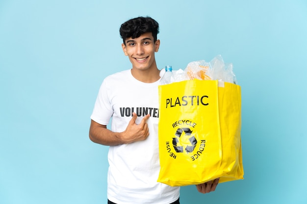 Joven argentino sosteniendo una bolsa llena de plástico con expresión facial sorpresa