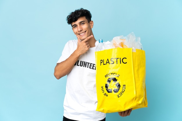 Joven argentino sosteniendo una bolsa llena de plástico feliz y sonriente
