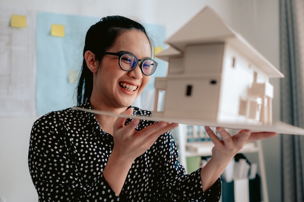 Foto joven arquitecta está mirando el nuevo modelo en el espacio industrial con grandes ventanas de fábrica