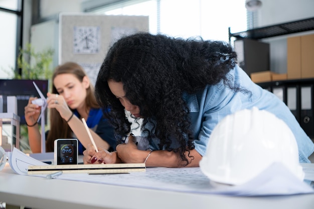 Joven arquitecta trabajando en un plano con un colega en la oficina